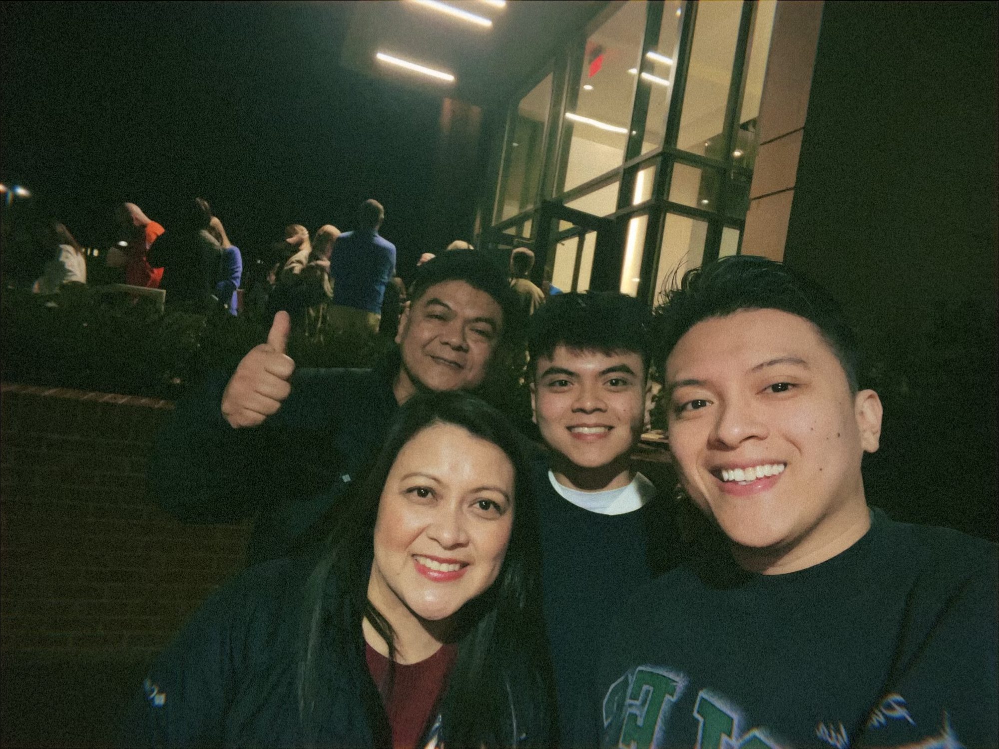 Raymond taking a selfie with his family outside at night